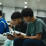 Programs 37 Young men reading and studying together at a church event in a modern indoor setting.