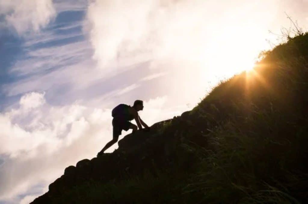 Insights 1 Person climbing a hill during sunset with sunlight shining behind.